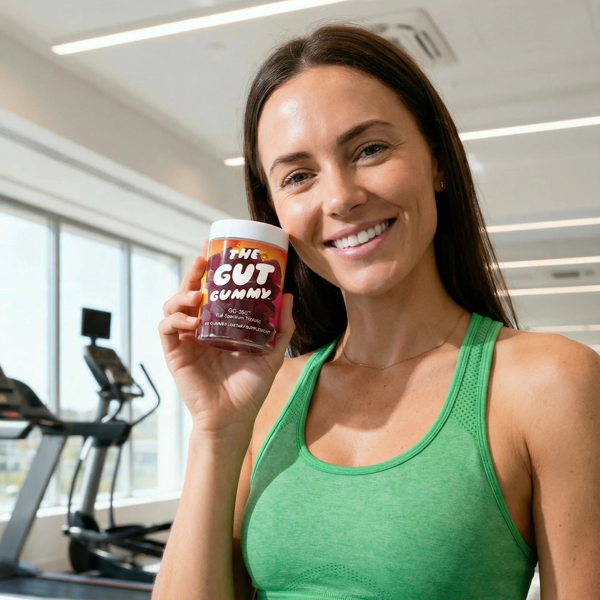 Woman in green athletic wear holding a container in a gym setting